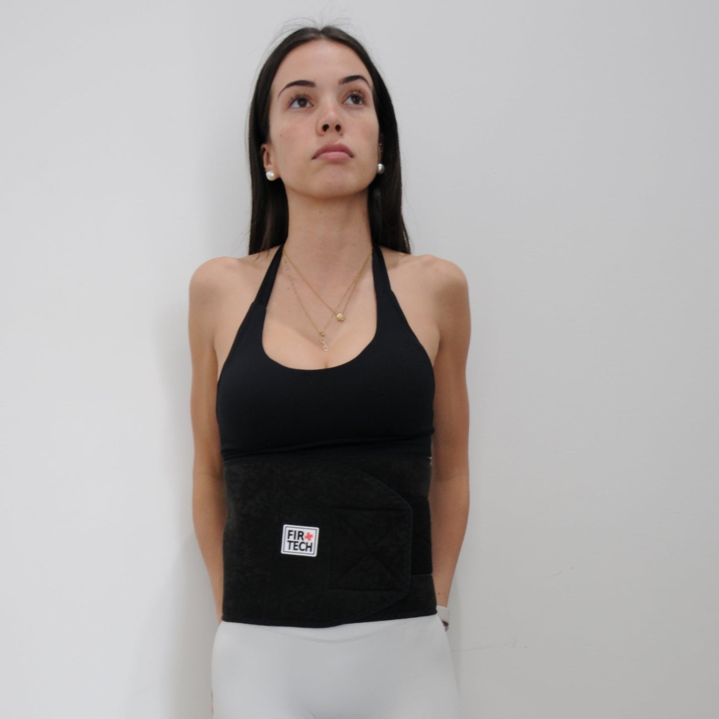 Woman in black tank top and white leggings standing on a light gray floor.