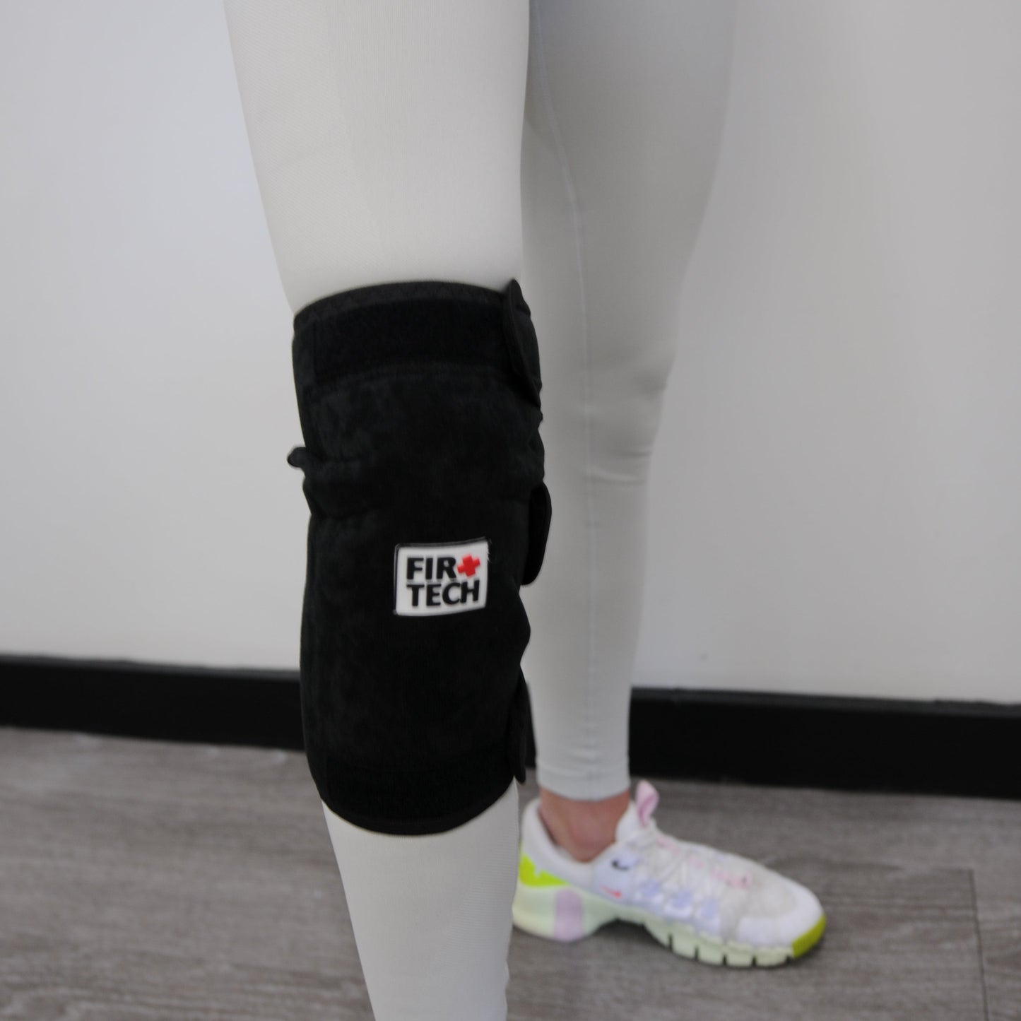 Person wearing black boxing gloves with a brand logo on a neutral background